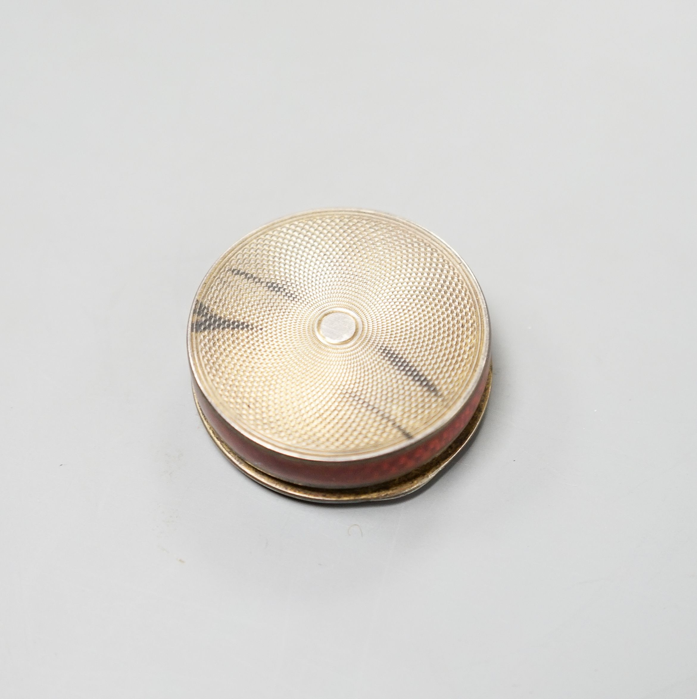 An early 20th century French engine turned white metal and red enamel circular pill box, 40mm.